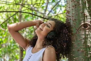 Beautiful afro american girl listening music in a park photo