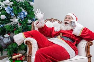 Santa Claus using a smartphone. Talking on the phone with child. Analyzing Christmas requests. photo