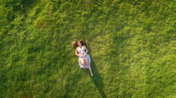 Aerial view. Young girl lying and resting on lawn on sunny day in park on grass. Above view. Woman on grass in meadow. photo