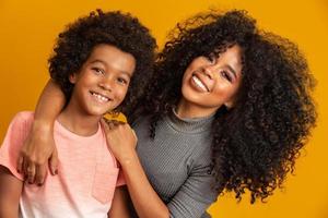 retrato de una joven madre afroamericana con un hijo pequeño. fondo amarillo familia brasileña. foto