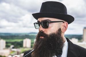 elegante hombre barbudo fumando pipa mirando el horizonte desde lo alto de un edificio alto. foto