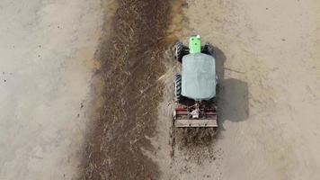 Los tractores verdes de vista superior aran el campo de arroz mojado