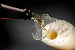 Beer pouring into a glass with foam on a dark background