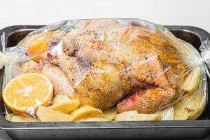 Raw chicken with spices, potatoes and oranges in a baking tray before baking photo