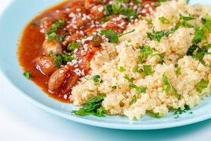 Closeup cereal couscous with spacely in tomato sauce and sesame seeds photo