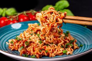 Close up of pasta with tomato sauce on wooden chopsticks
