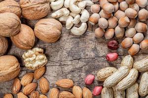 Peanuts, walnuts, almonds, cashews and hazelnuts on old wooden background photo