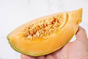 Sliced Melon in the hand above white background photo