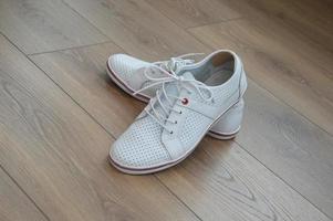 A pair of stylish sports shoes on a brown wooden floor. Inserts on the back of the shoe from calluses on the heels. photo