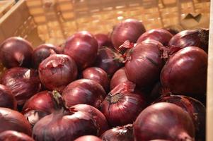 Red onions are on display in abundance on the supermarket counter. Fresh vegetables, harvesting. Vegetarian food. photo