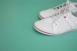 White sports shoes, gumshoes on a mint green background. View from above. Free space for text. Modern shoes for sports, walking, running. photo
