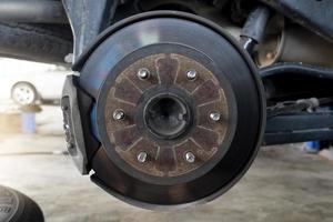 Maintenance background of car's suspension with the rear wheels removed reveals disc brakes. photo