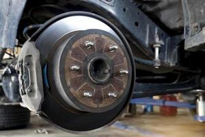 Maintenance background of car's suspension with the rear wheels removed reveals disc brakes. photo