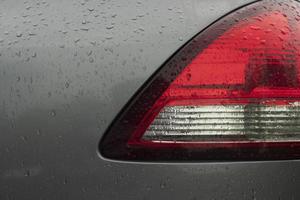 Close up beside of tail light red and white color. Car gray color. On the boy with drop of rain. photo