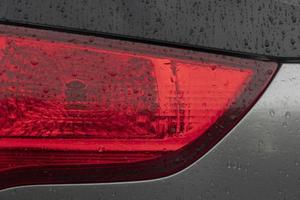 Close up tail light red color. Car gray color. On the boy with drop of rain. photo