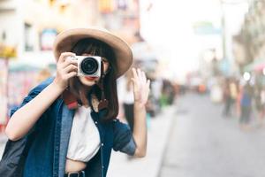 una joven viajera asiática toma una foto con una cámara en la calle khaosan.
