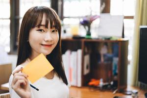 Young asian teenager woman hold a note paper work and study at home photo
