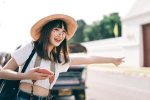 una joven viajera asiática llama a un taxi para hacer turismo en bangkok. foto