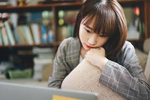 una adolescente asiática trabaja y estudia en línea a través de Internet en casa. foto