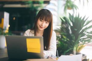 Young adult asian college student woman using laptop at cafe. photo