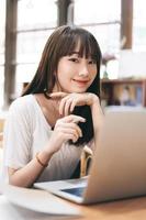 joven mujer asiática adolescente aprendiendo en línea en casa a través de una computadora con internet foto