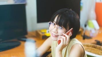 una mujer asiática adulta joven se queda y trabaja desde la oficina en casa usando un teléfono inteligente en el interior el día. foto