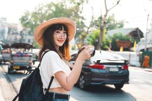 joven mujer asiática mochila viaje en ciudad con cámara foto