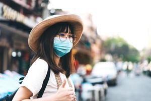 joven viajera asiática con gafas, sombrero y máscara, protege pm 2.5 y virus.