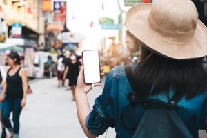 maqueta de la pantalla blanca en blanco del teléfono inteligente con una mujer asiática viajera.