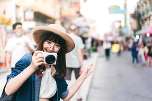 una joven viajera asiática toma una foto con una cámara en la calle khaosan.
