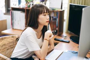 mujer adolescente asiática usa computadora para trabajar y estudiar educación en línea foto