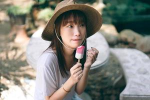 Portrait of cute asian teenager woman eating ice cream at outdoor garden. photo