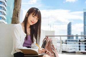 Single young adult asian student woman sit and studying with notebook at campus area. photo