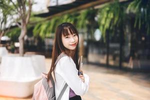 Portrait of young adult asian college student woman with notebook on day in the city. photo