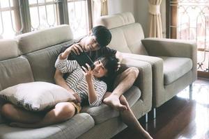pareja de jóvenes adultos amantes asiáticos sentados en el sofá y jugando al estilo acogedor interior el día. foto