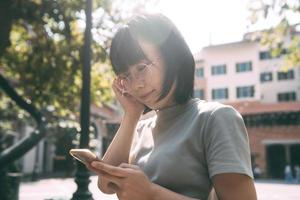 Young adult happy asian woman wear eyeglasses using mobile phone for social media. photo