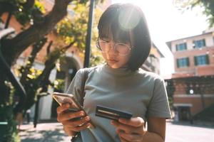 Consumidor de mujeres asiáticas de negocios de adultos jóvenes que usa tarjeta de crédito y teléfono inteligente para comprar en línea.