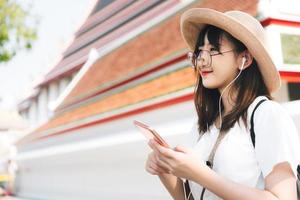 Young asian travel energetic girl listen streaming music with smart phone. photo