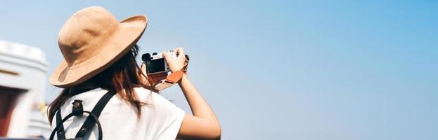 Young asian woman traveller with camera for banner size background. photo