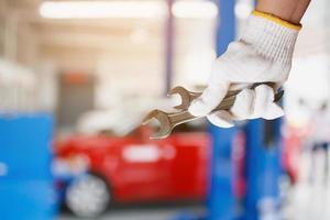 Car mechanic holding wrench at the car repair garage photo