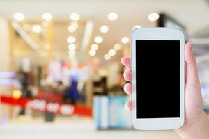 mano sostenga el teléfono móvil en el centro comercial foto