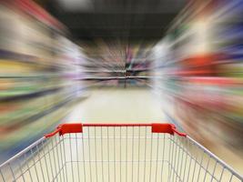 vista de carrito de compras de supermercado con desenfoque de movimiento de pasillo de supermercado foto