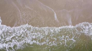 vista aérea de arriba hacia abajo ola blanca golpeada en la arena