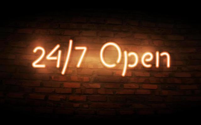 Neon Open 24 7 sign on brick wall background.