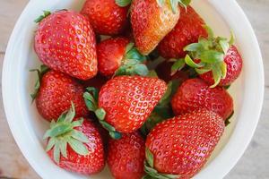 Ripe red strawberries on wooden table photo