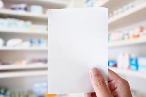 mano de farmacéutico con papel de prescripción en blanco en la farmacia foto