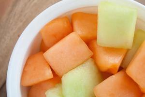 closeup melon slice in white dish with wood table background photo