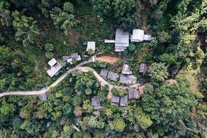 Aerial view of local rural village with gravel road through in the valley on faraway at countryside among the tropical rainforest photo