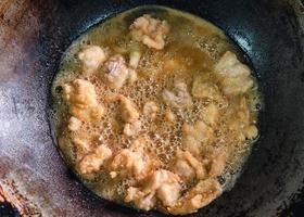 Frying crispy fried chicken meat with boiling oil in fry pan on gas stove photo