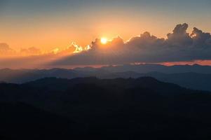Sunset shining through cloud over mountain range in tropical rainforest at national park photo